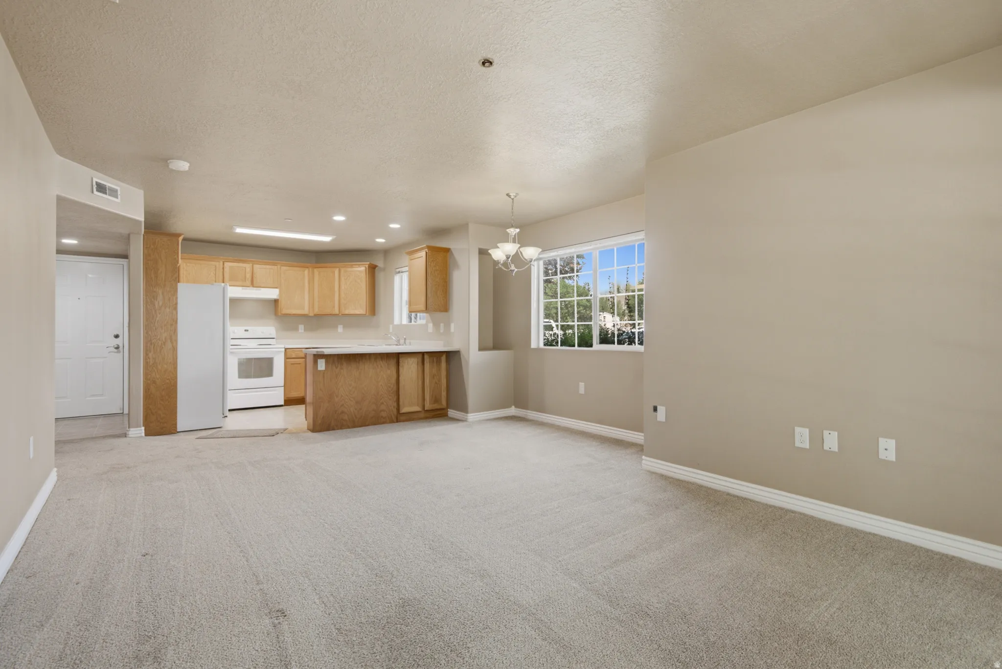 Open concept living space with light-toned carpeting and neutral wall tones