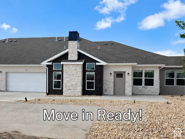 Exterior featuring stone accents, dark siding, an attached garage, and a covered entry