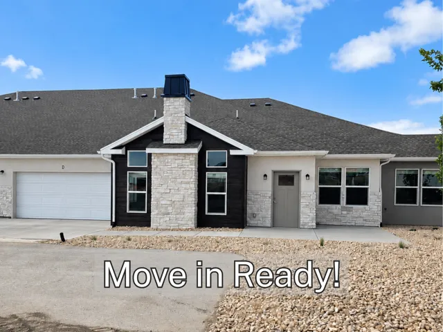 Exterior featuring stone accents, dark siding, an attached garage, and a covered entry