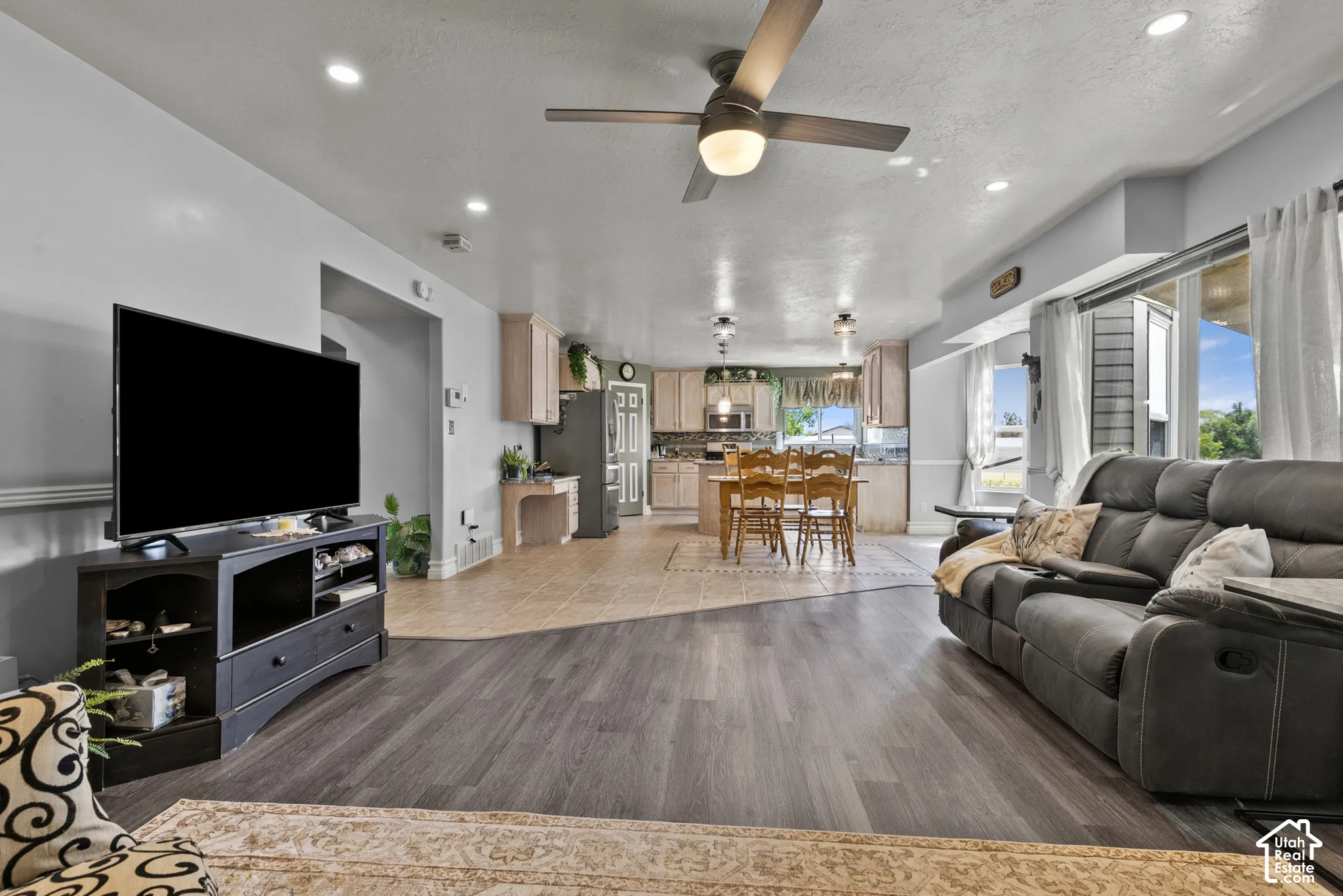 Open-concept living area with wood-finish flooring, recessed lighting, and a ceiling fan