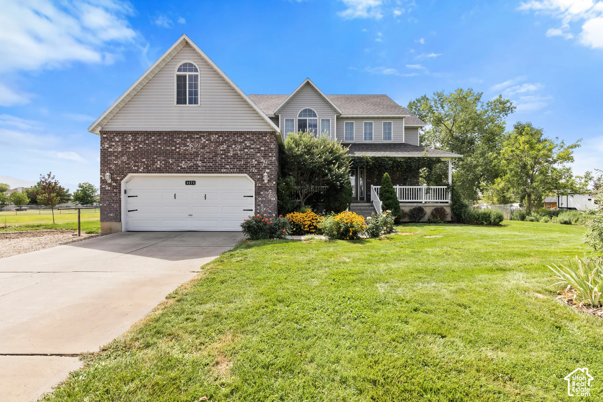 Brick and siding exterior with an attached two-car garage, covered front porch, and mature landscaping