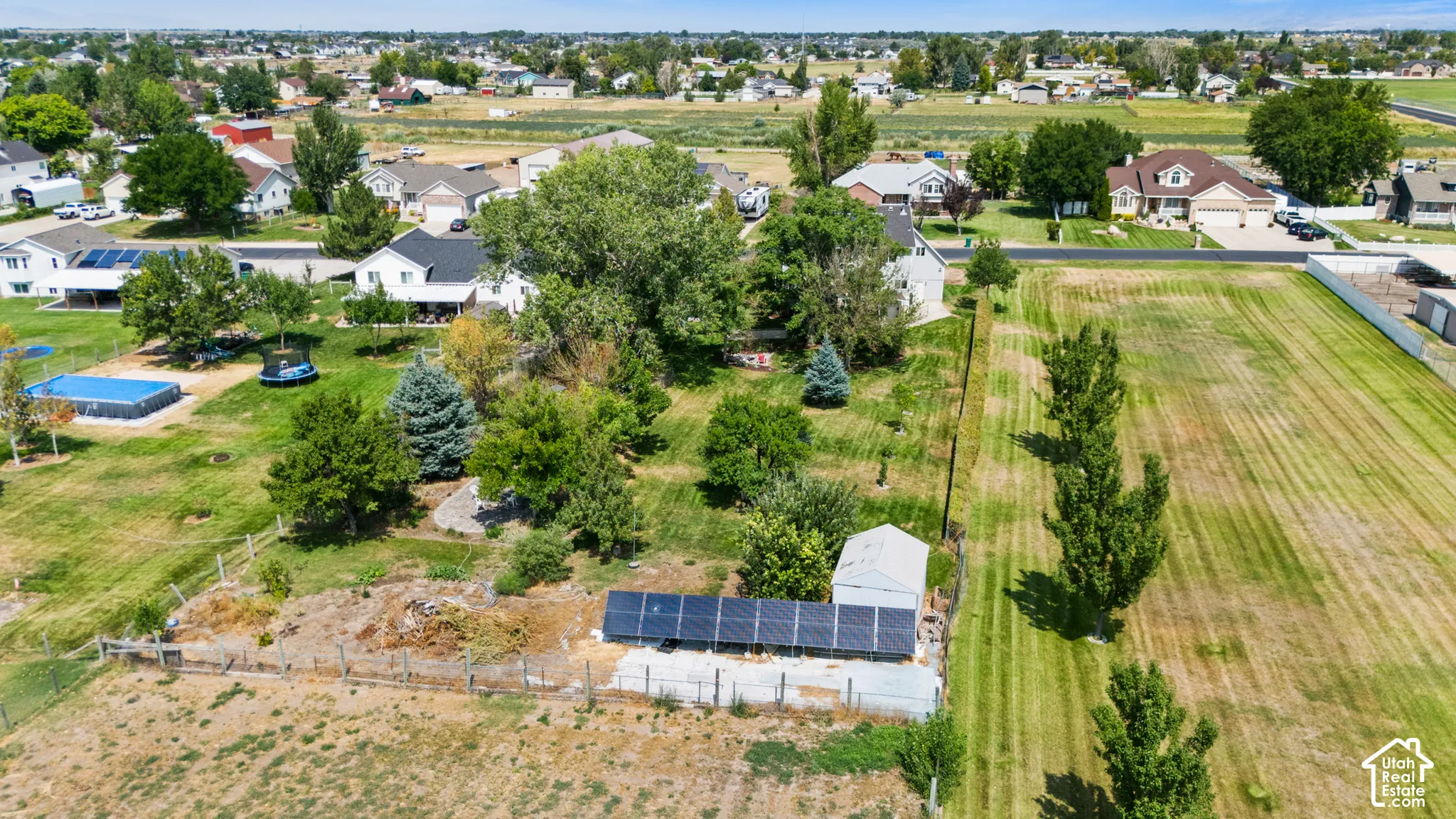 Expansive outdoor area featuring mature trees, a detached shed, and ground-mounted solar panels