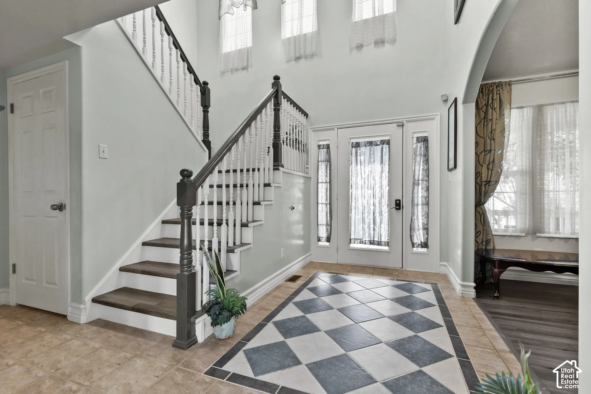 Foyer featuring a grand staircase with dark wood-finish banisters and white spindles
