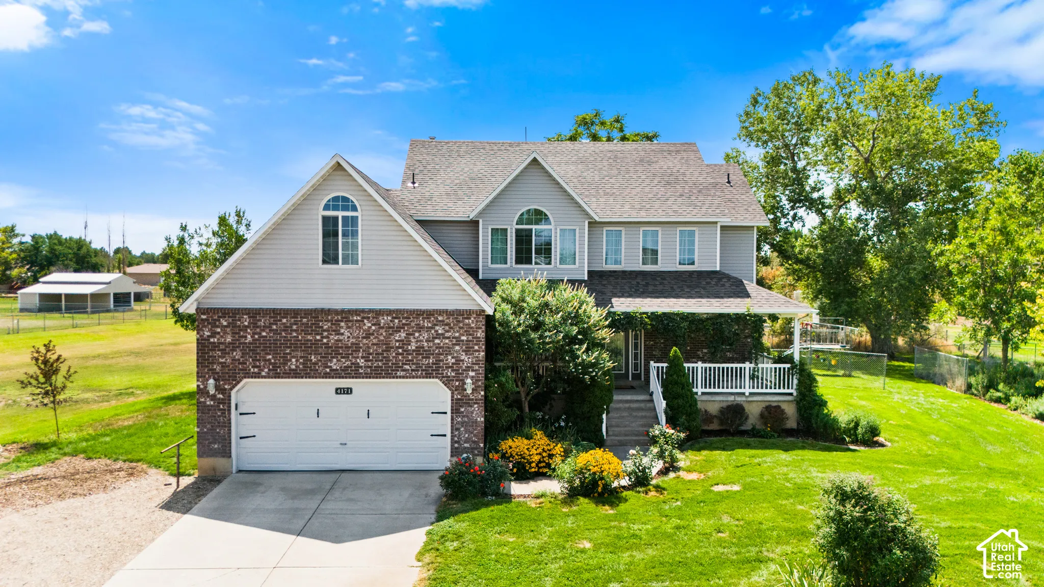 Residence with a two-car garage, brick veneer and siding exterior, front porch with white railing, and a gabled roof