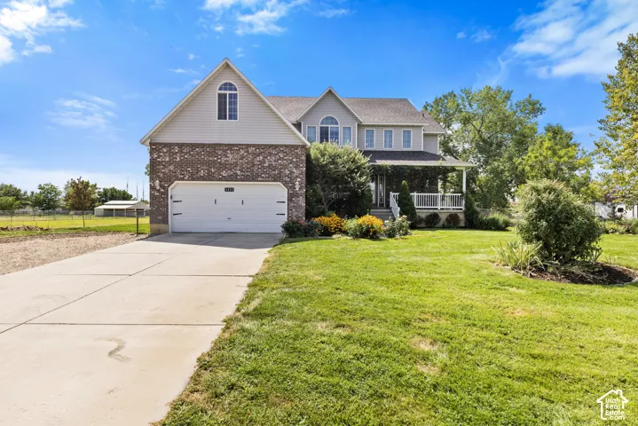 Two-story home featuring a brick and siding exterior, an attached two-car garage, and a covered front porch