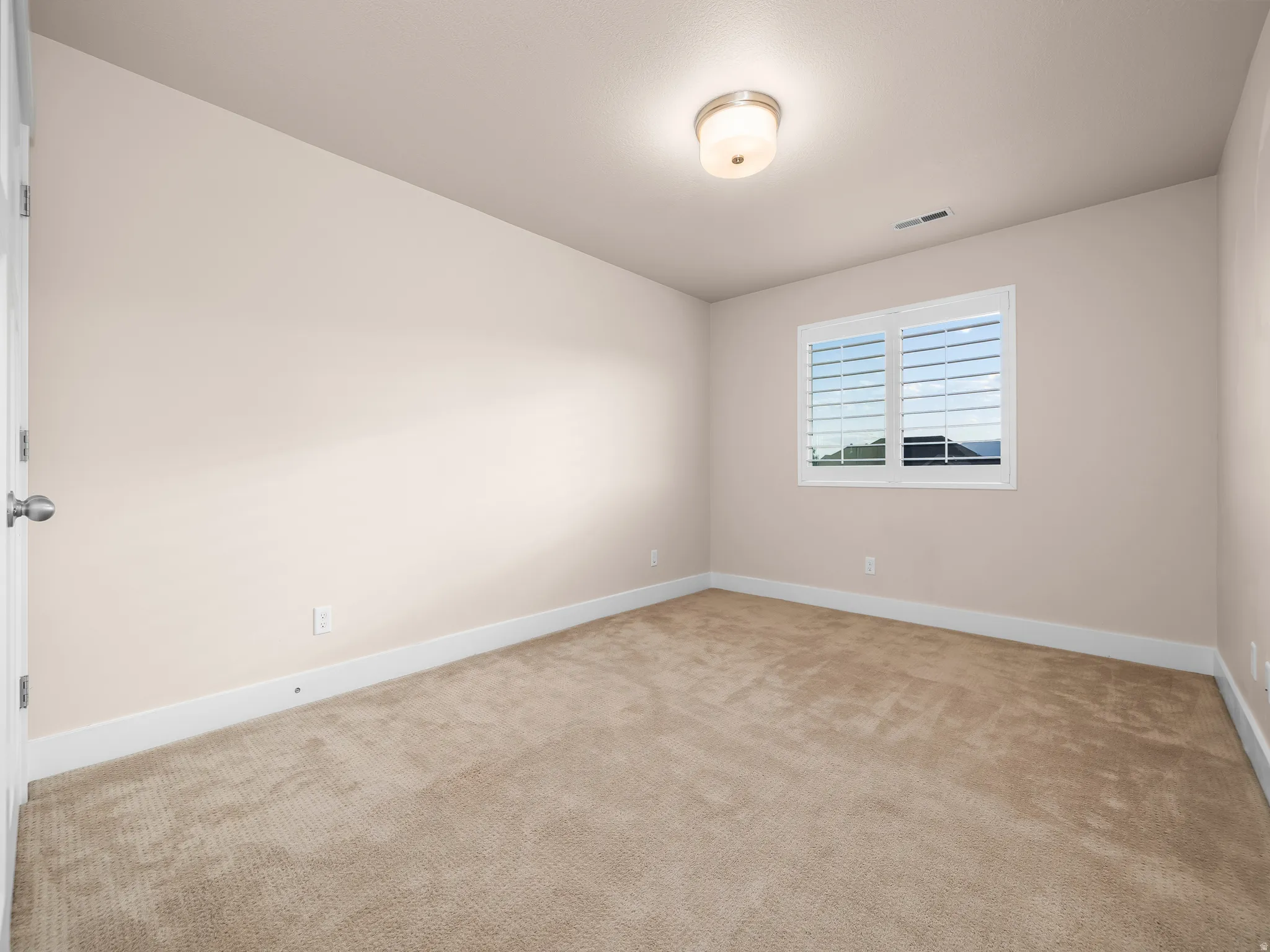 Neutral wall tones, recessed lighting fixture, window with louvered blinds, and plush carpeting