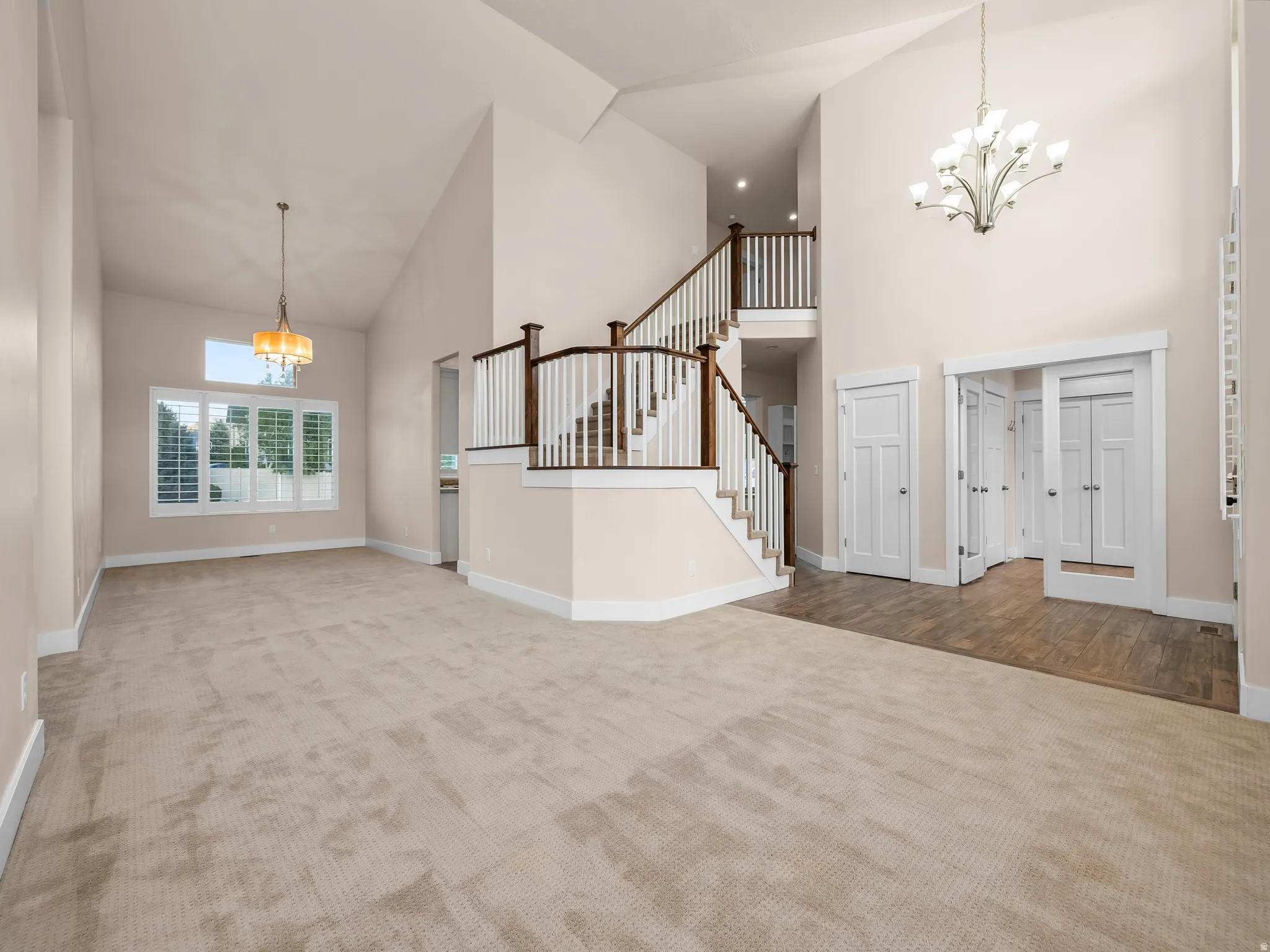 Vaulted ceilings, open staircase with wood-finish handrails, white balusters, and white risers, carpeted flooring, and wood-finish flooring