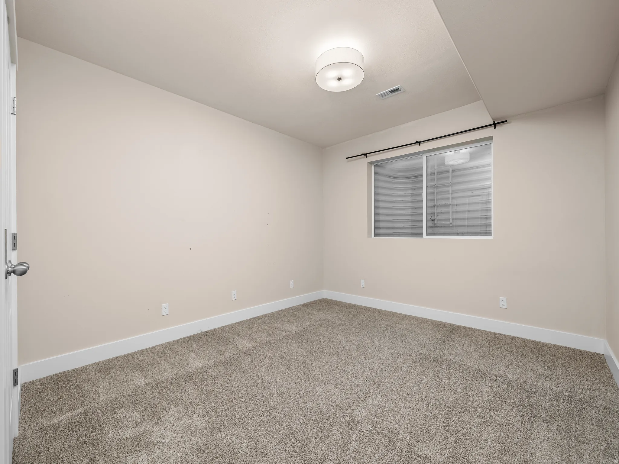 Neutral-toned walls, plush carpeting, and a modern flush-mount ceiling light