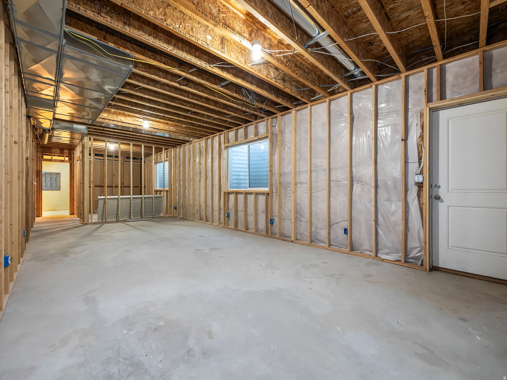 Unfinished basement with exposed wood framing, concrete flooring, and multiple egress windows