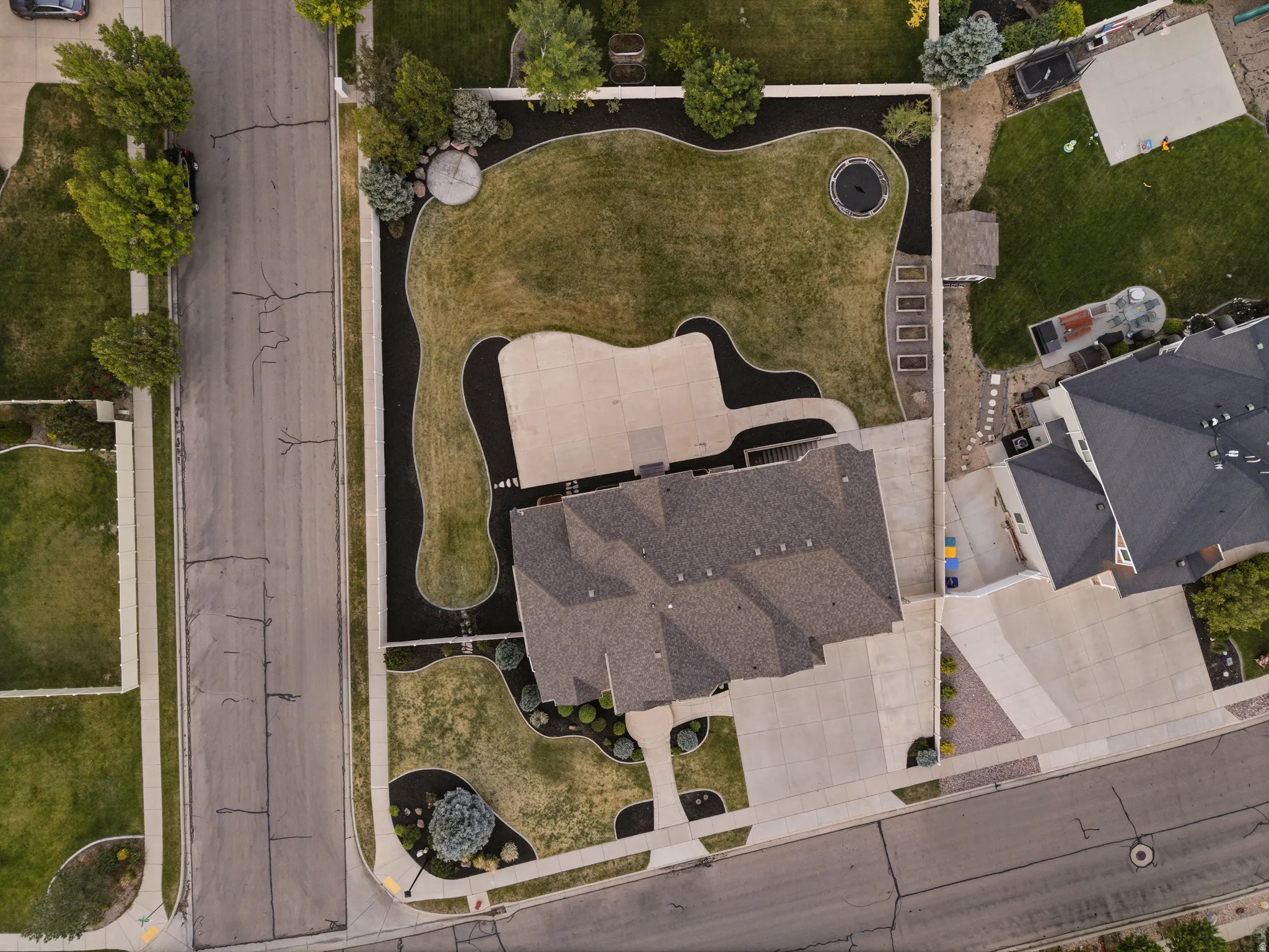 Expansive backyard featuring a manicured lawn, concrete patio, and built-in landscape beds