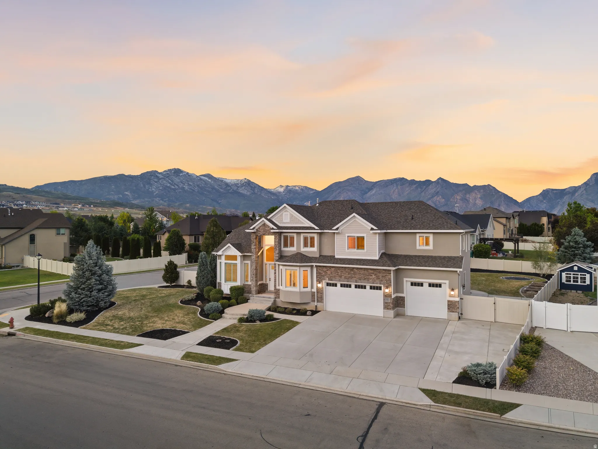 Two-story residence featuring a stone and stucco exterior, prominent bay windows, and two two-car garages