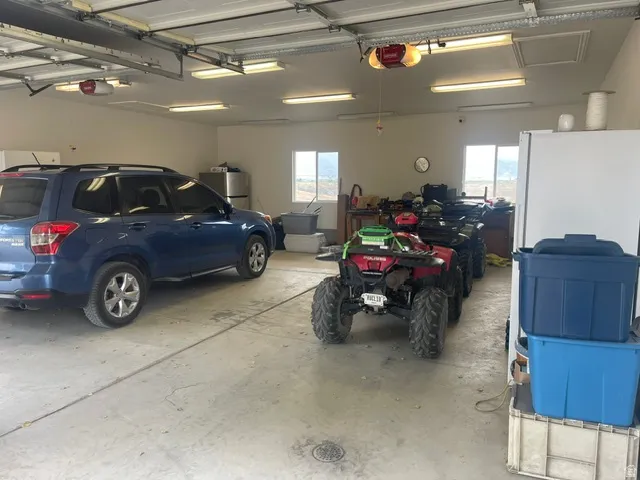 Spacious garage featuring concrete flooring, multiple windows, overhead lighting, and two overhead garage doors