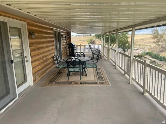 Covered porch with a log-style exterior, white railing, and sliding glass door access
