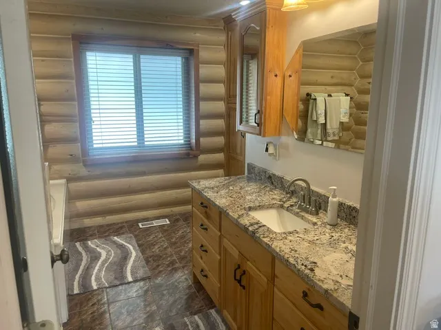 Wood-paneled walls, a vanity with a light-toned countertop, a built-in sink, and a framed mirror