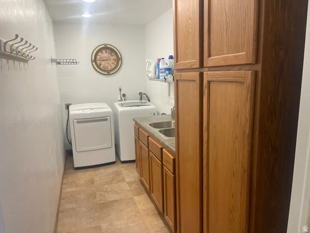 Functional utility space featuring a double basin sink, wood-finish cabinetry, and tiled flooring