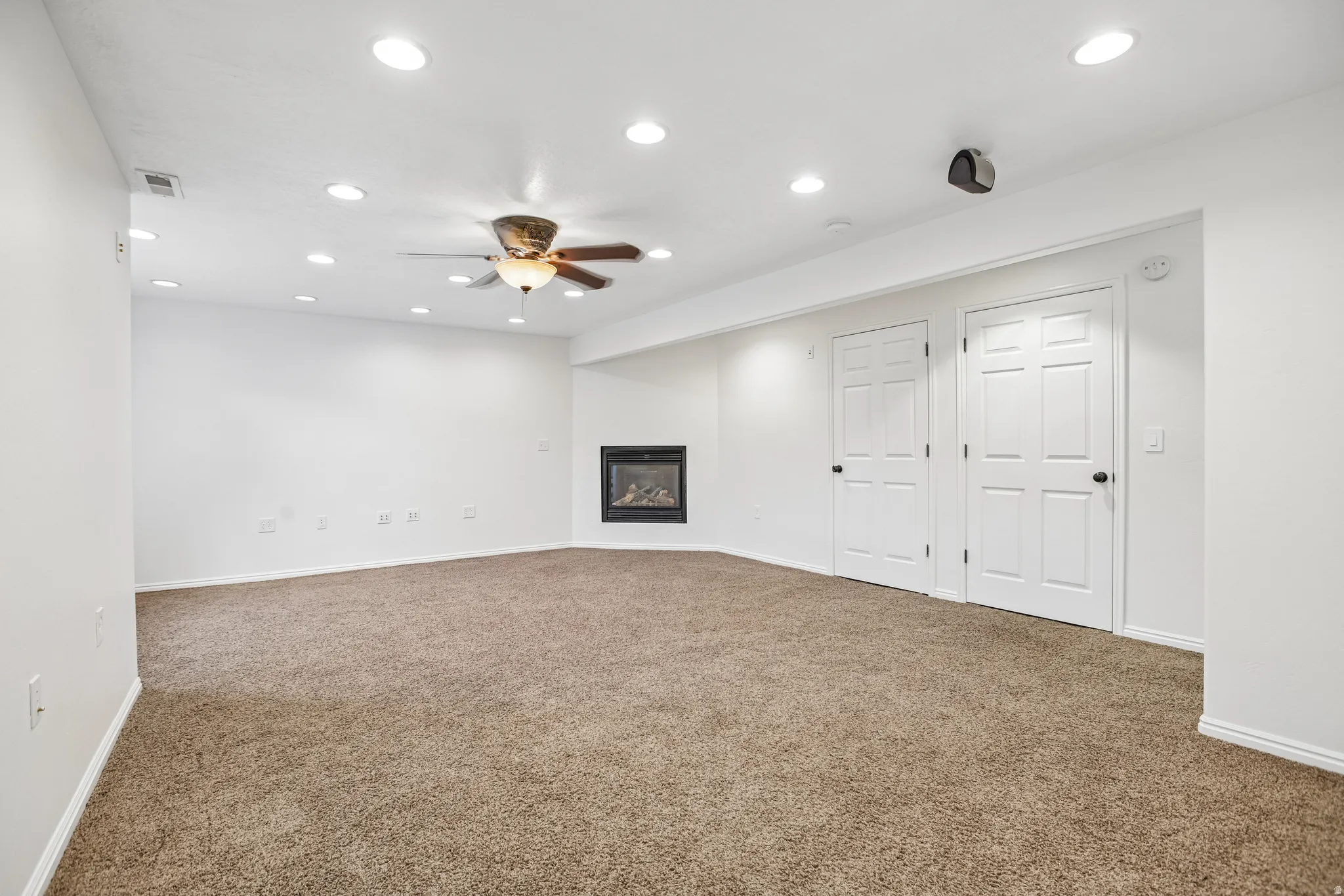 Recessed lighting, ceiling fan, brown carpet flooring, electric fireplace, and two paneled interior doors