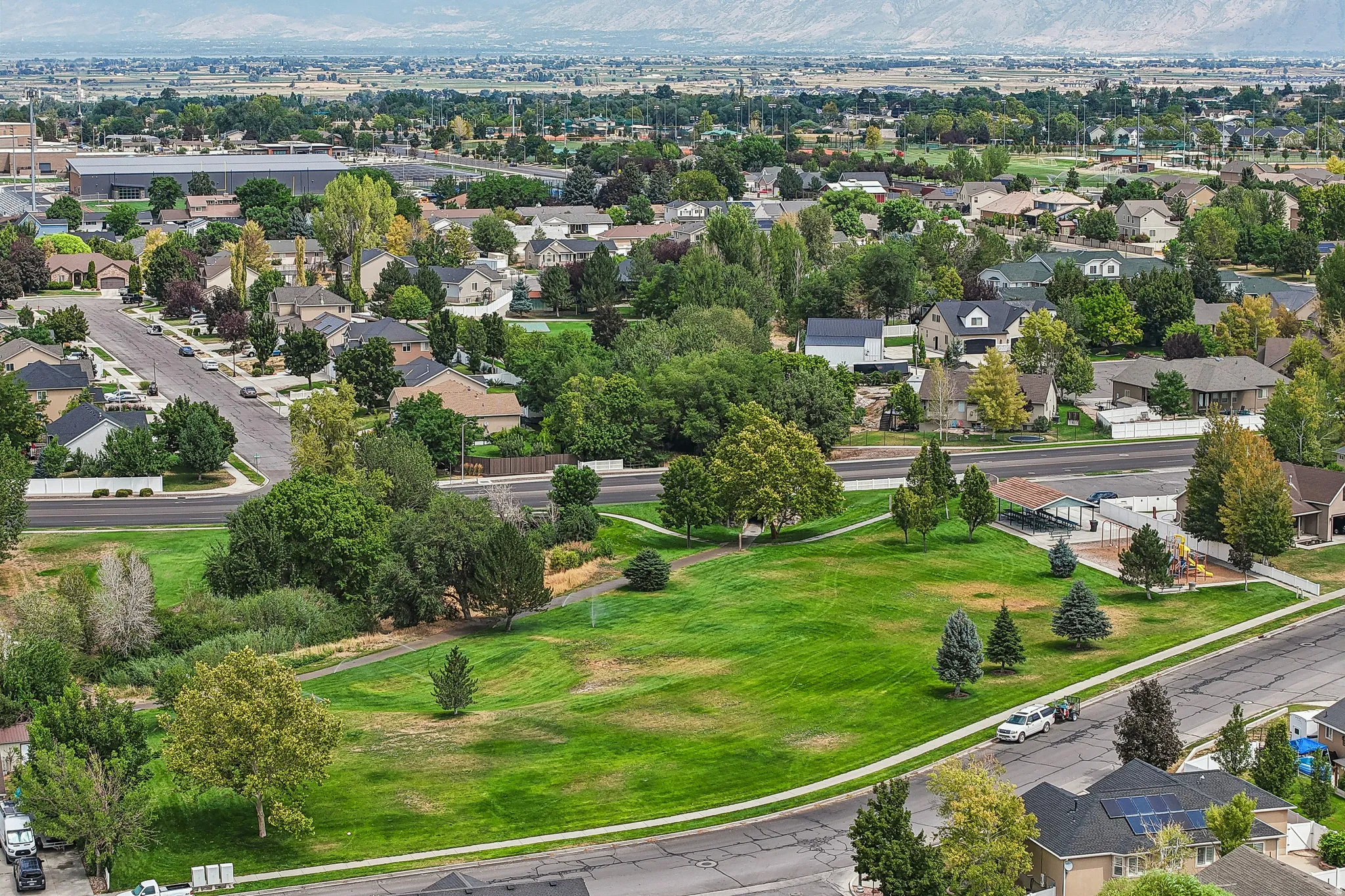 Expansive green space featuring mature trees and mountain scenery