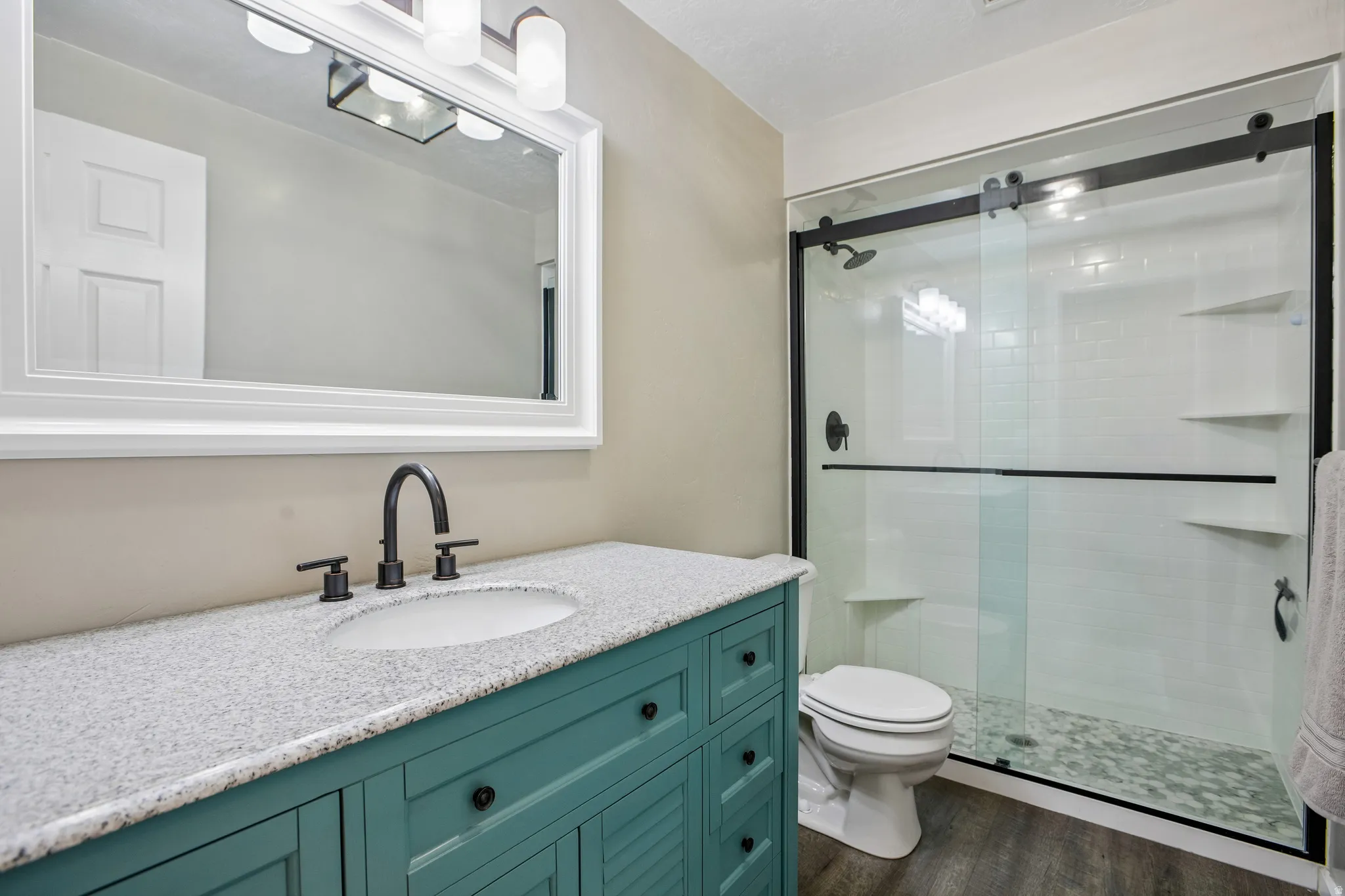 Modern vanity with a speckled countertop, matte black faucet, and painted wood cabinetry