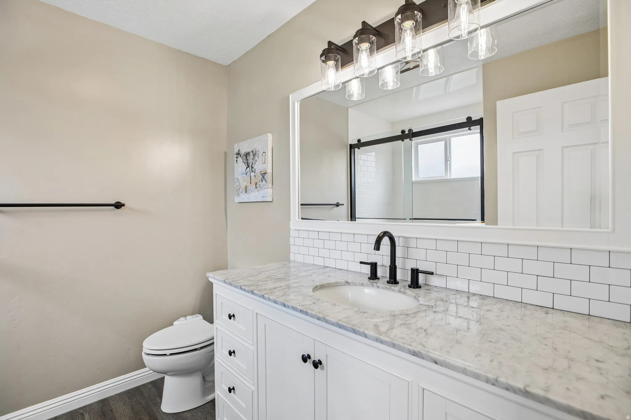 White shaker vanity with black hardware, undermount sink, and marble countertop