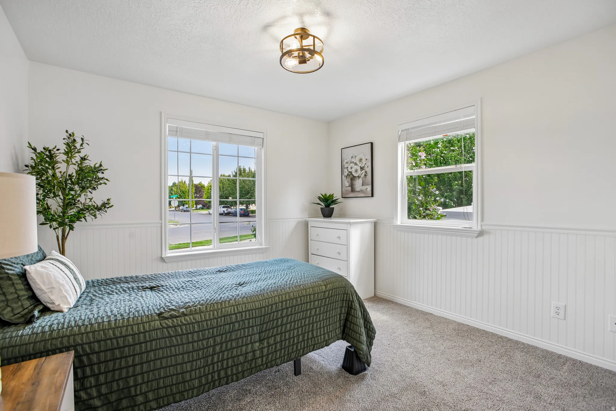 White wainscoting paneling, two windows with grid detailing, recessed ceiling light fixture, and plush carpeting