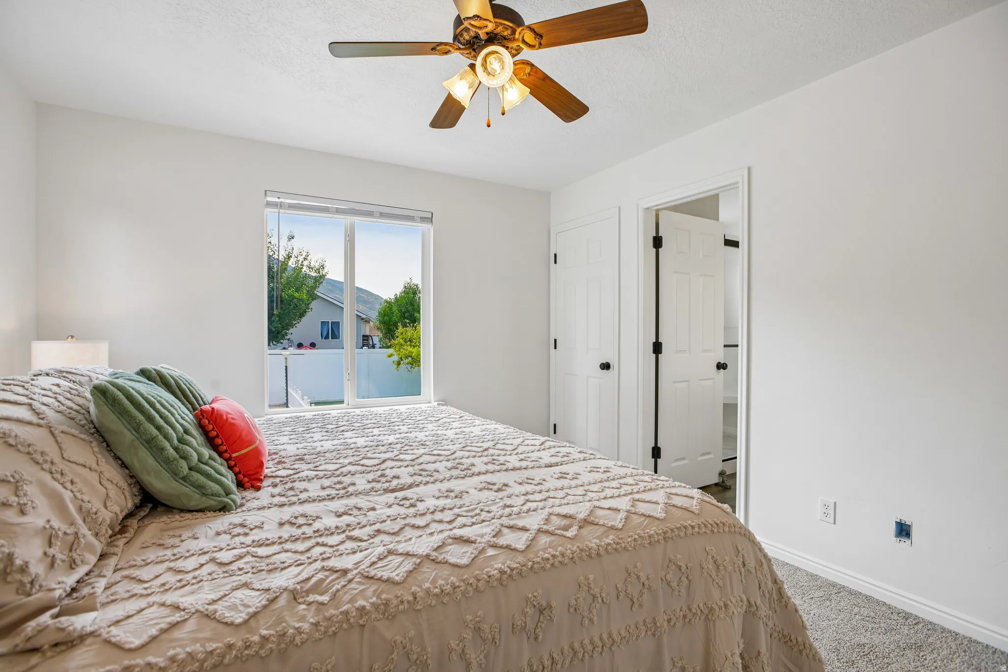 Bright interior with a ceiling fan, white walls, and a large window