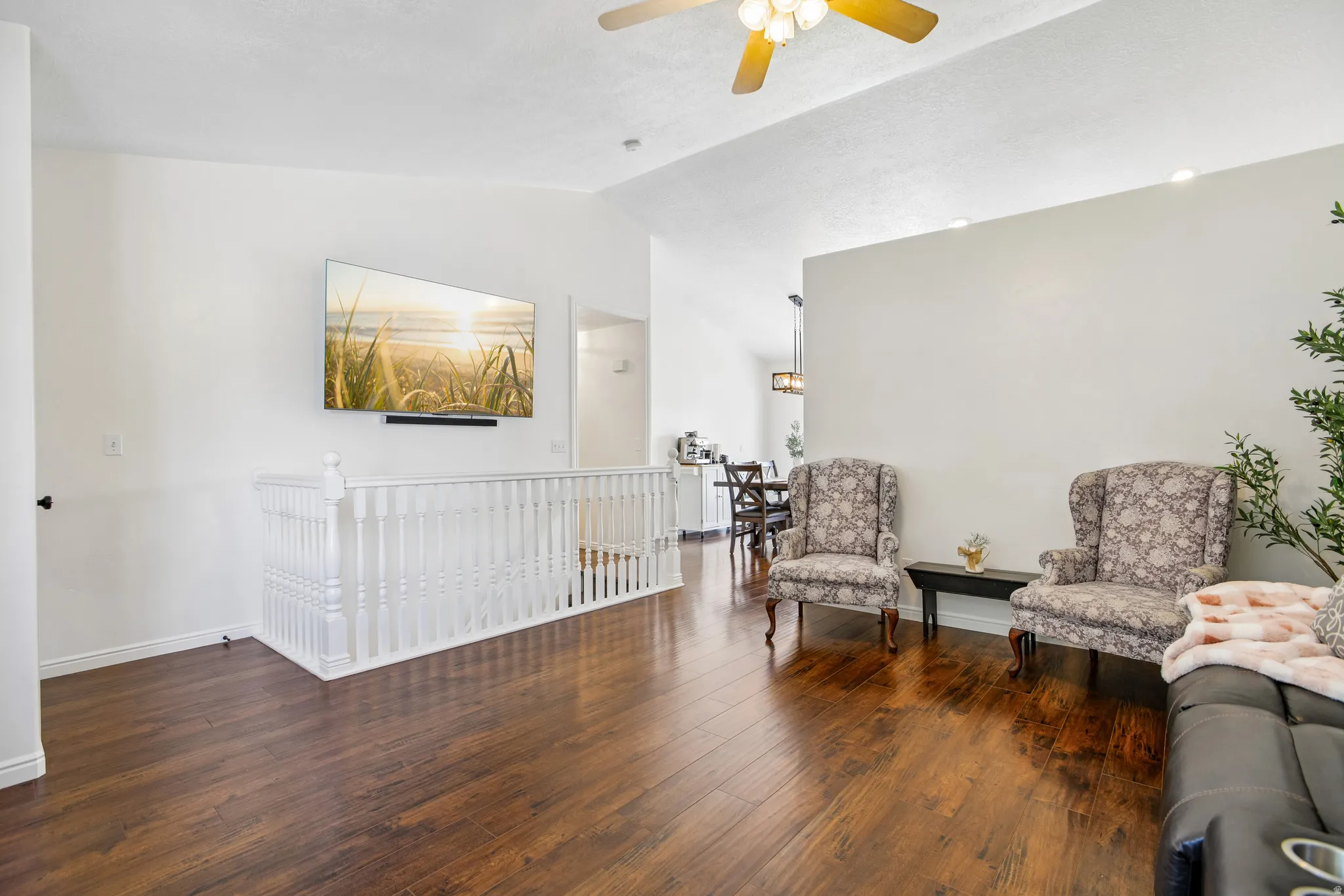 Vaulted ceiling with a ceiling fan, wood-finish flooring, and white wall finishes