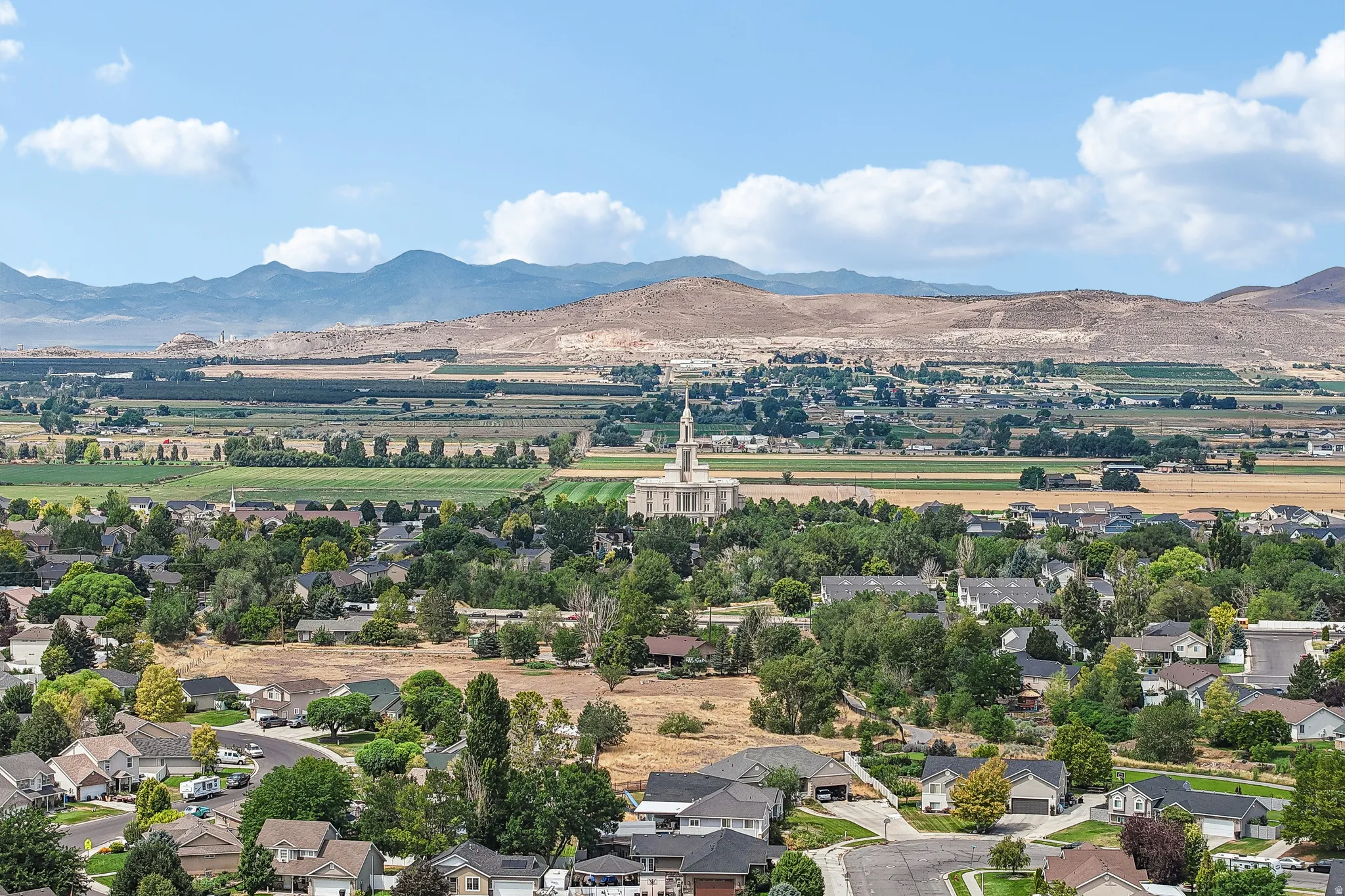 Expansive neighborhood setting featuring a variety of residential structures, mature trees, and mountainous backdrops
