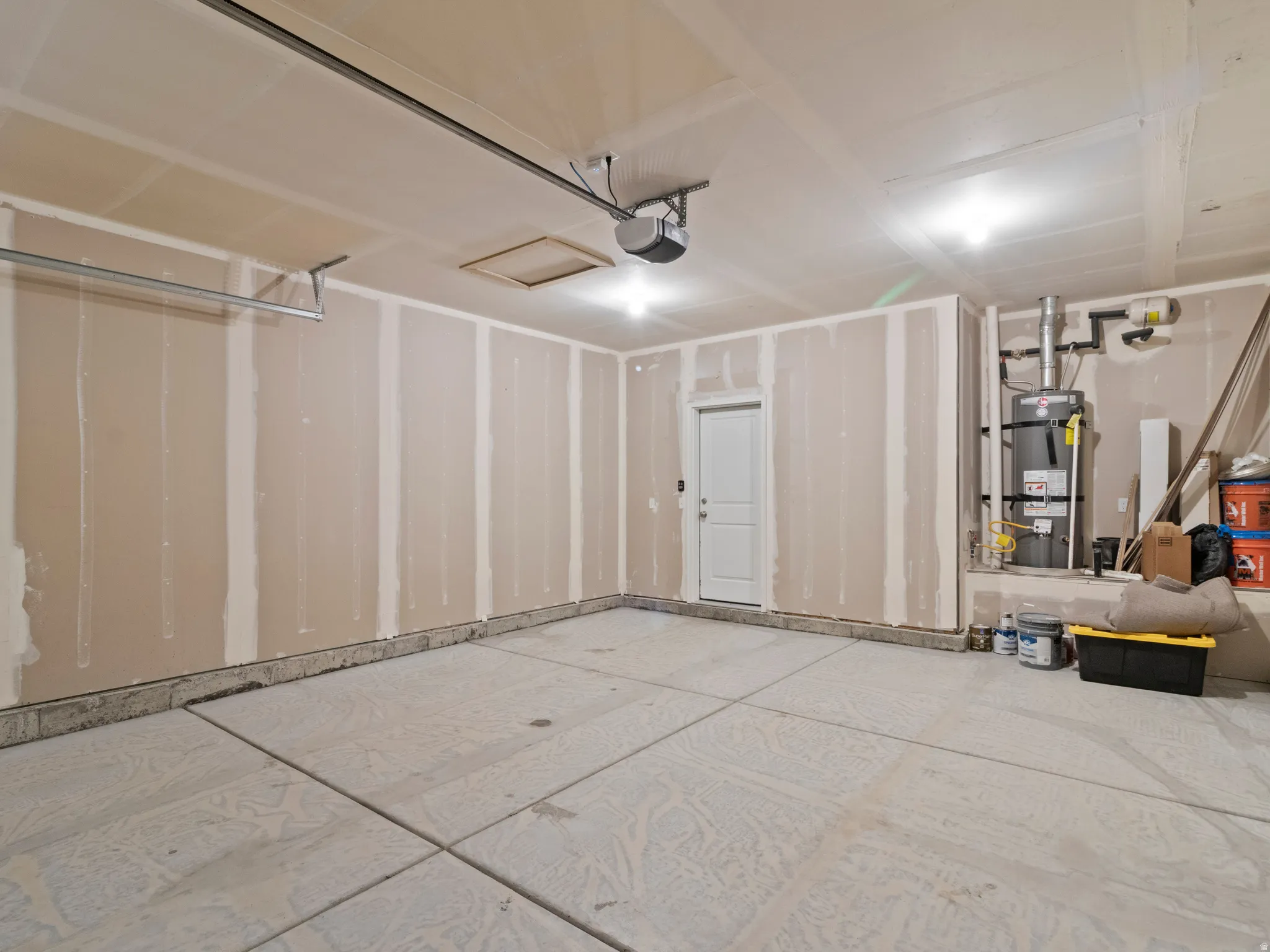Spacious garage with exposed drywalled walls, concrete flooring, and an overhead garage door opener mechanism