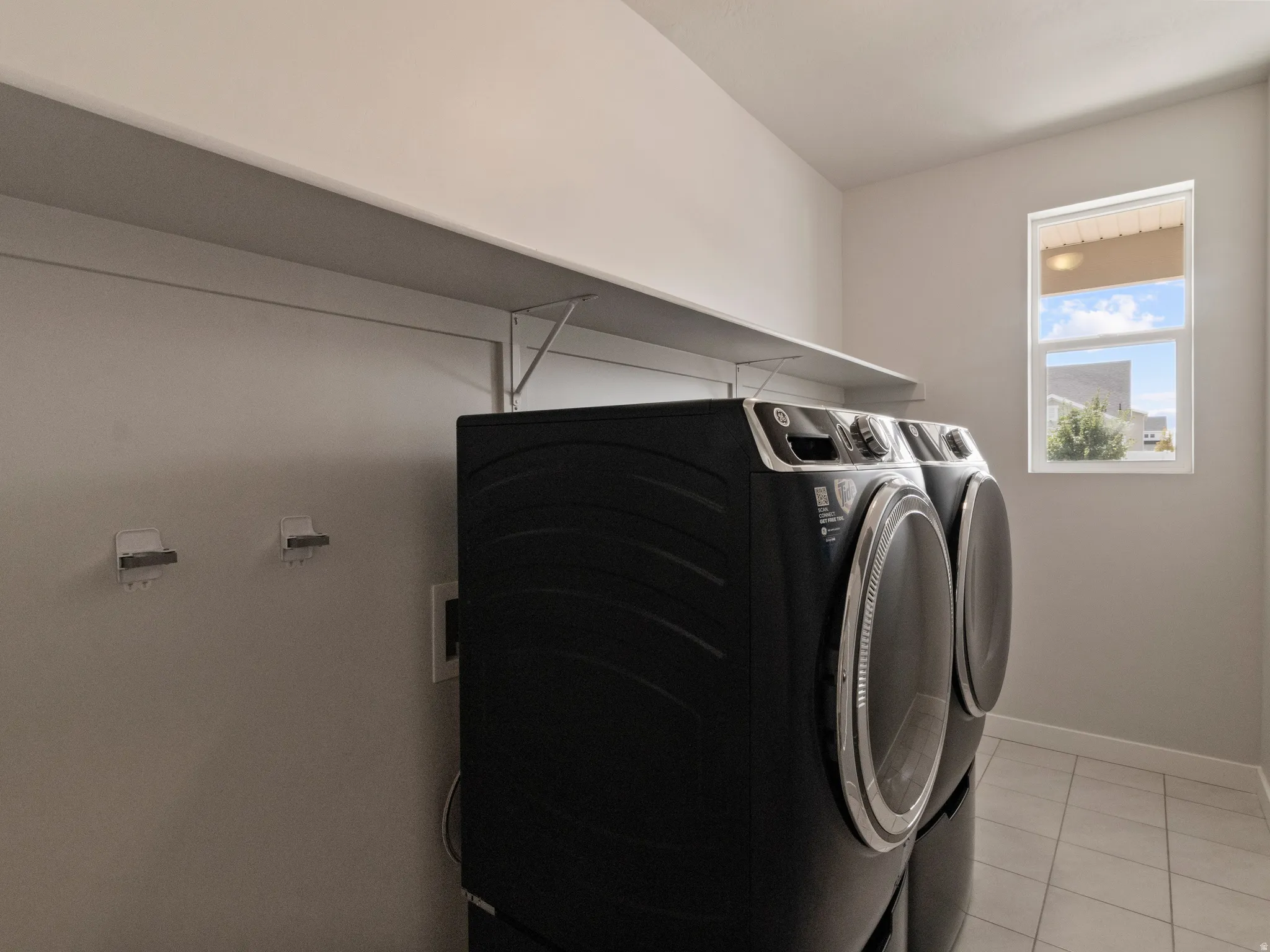Laundry area with white shelving, a single window, and tiled flooring