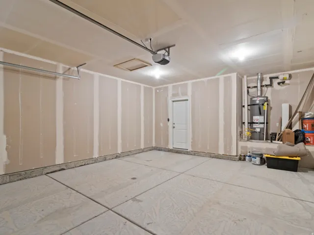Spacious garage with exposed drywalled walls, concrete flooring, and an overhead garage door opener mechanism