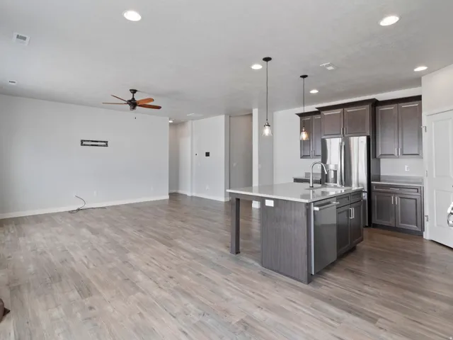 Open-concept living area with wood-finish flooring, recessed lighting, and a ceiling fan