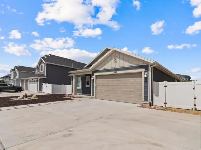 Modern exterior with blue siding, a two-car garage, white fencing, and a concrete driveway
