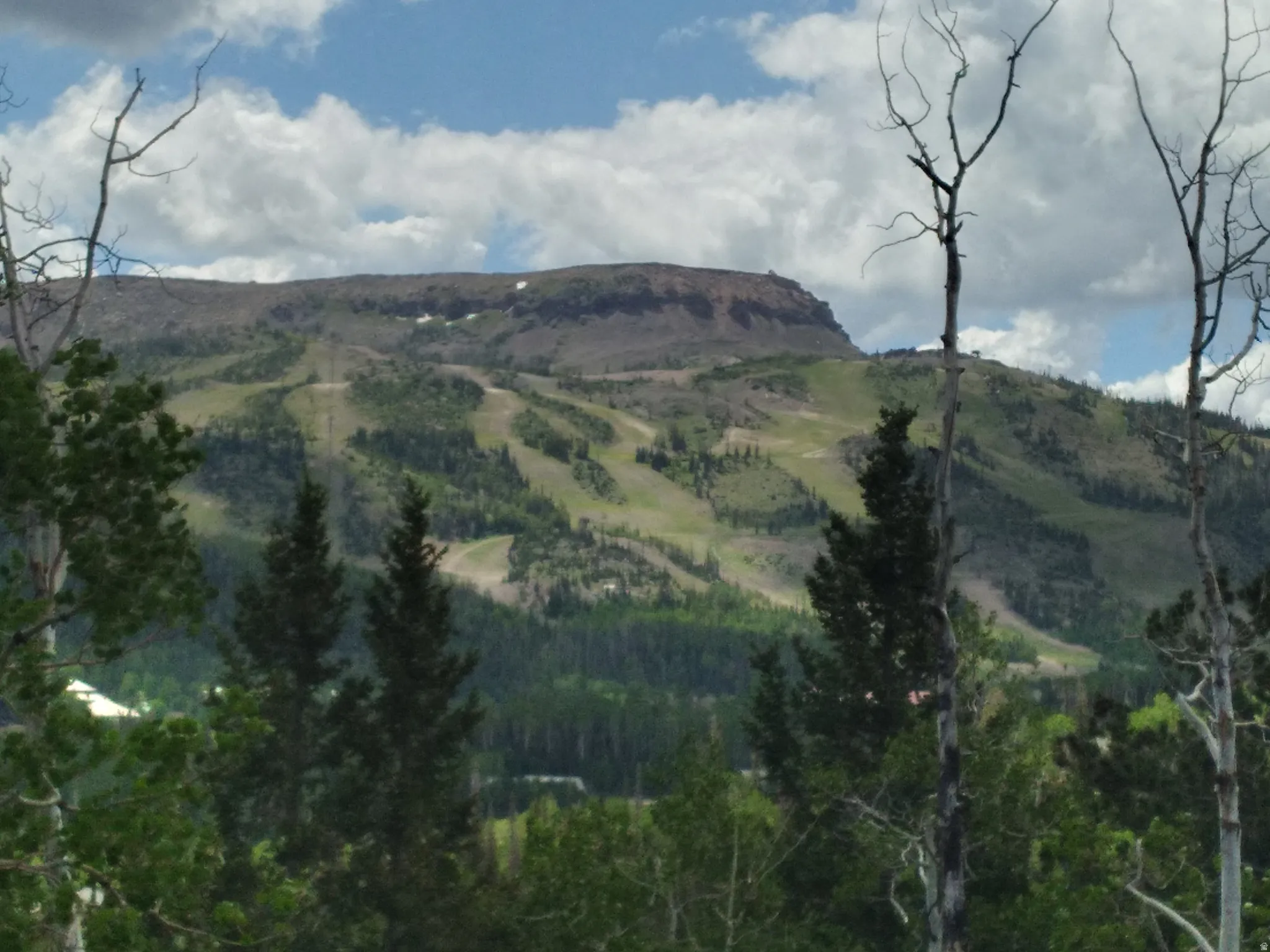 Mountainous terrain with green slopes and distant structures