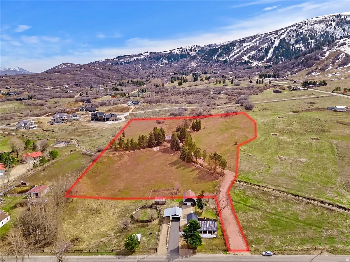 Expansive parcel with clear boundary outline, multiple structures, and established trees