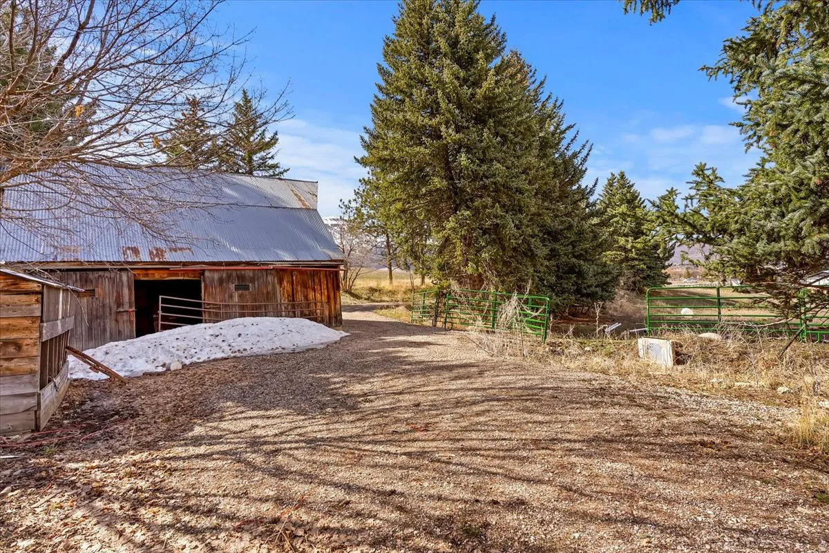 Rustic barn structure with a corrugated metal roof, wood siding, and an open entryway