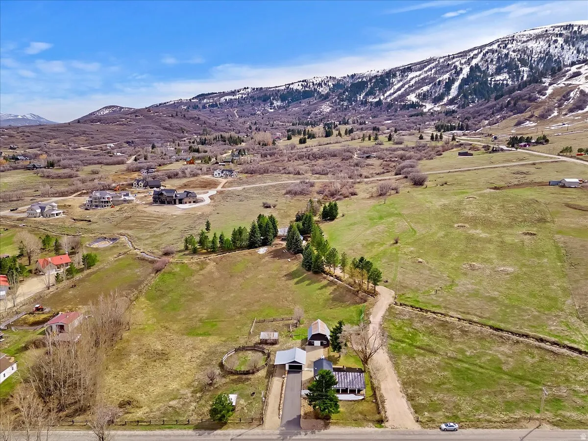 Expansive property featuring a paved driveway, multiple structures, and surrounding natural landscape with distant snow-capped mountains