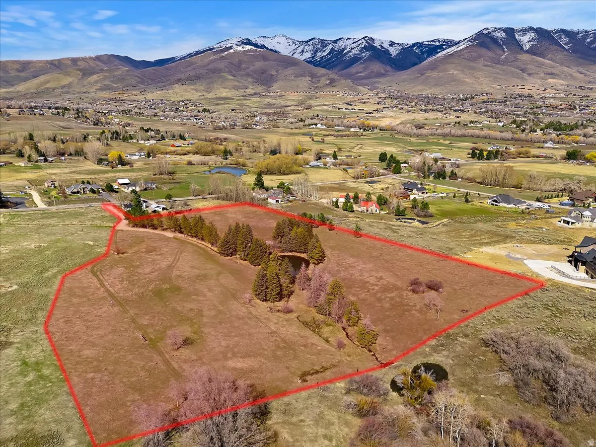 Expansive land parcel featuring natural terrain, mature trees, and a visible pond