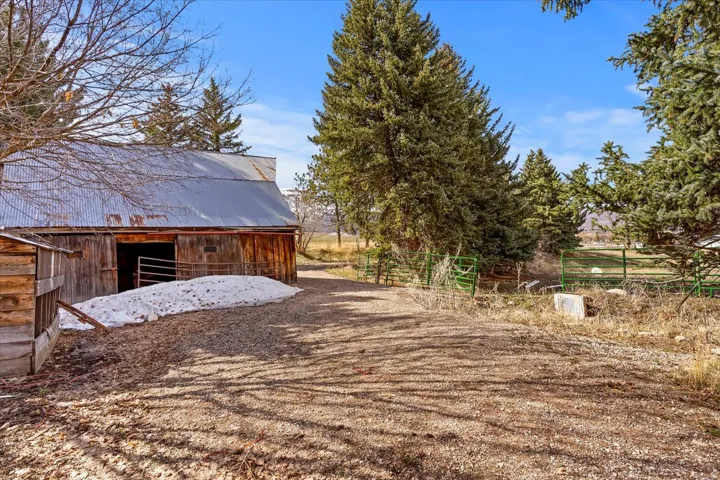 Rustic barn structure with a corrugated metal roof, wood siding, and an open entryway