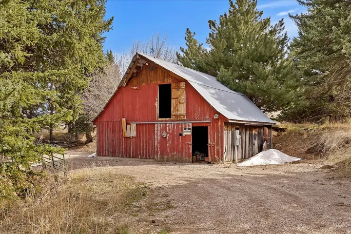 Red barn structure with a gambrel roof and natural wood accents