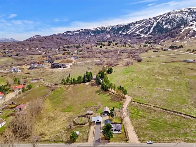 Expansive property featuring a paved driveway, multiple structures, and surrounding natural landscape with distant snow-capped mountains