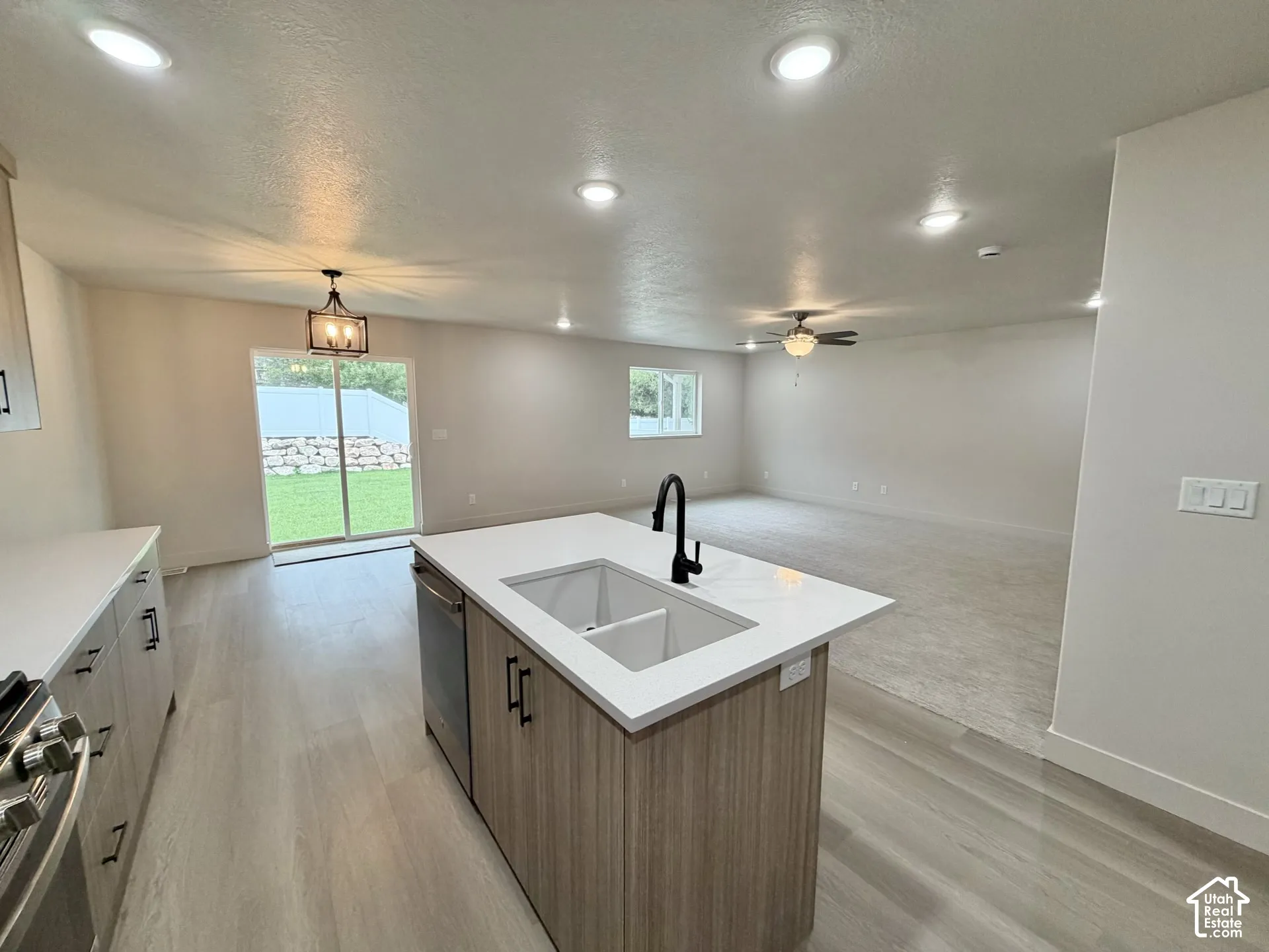 Kitchen featuring an island with a white quartz countertop, dual-basin undermount sink, matte black faucet, wood-finish cabinetry, and recessed lighting