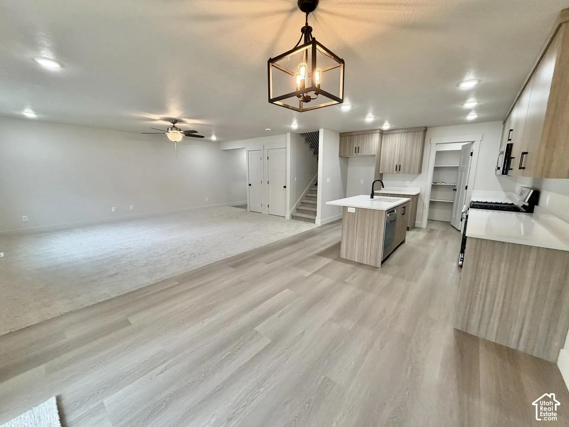 Open-concept area featuring wood-finish flooring, a kitchen island with quartz countertops, custom cabinetry, recessed lighting, and a geometric pendant light fixture