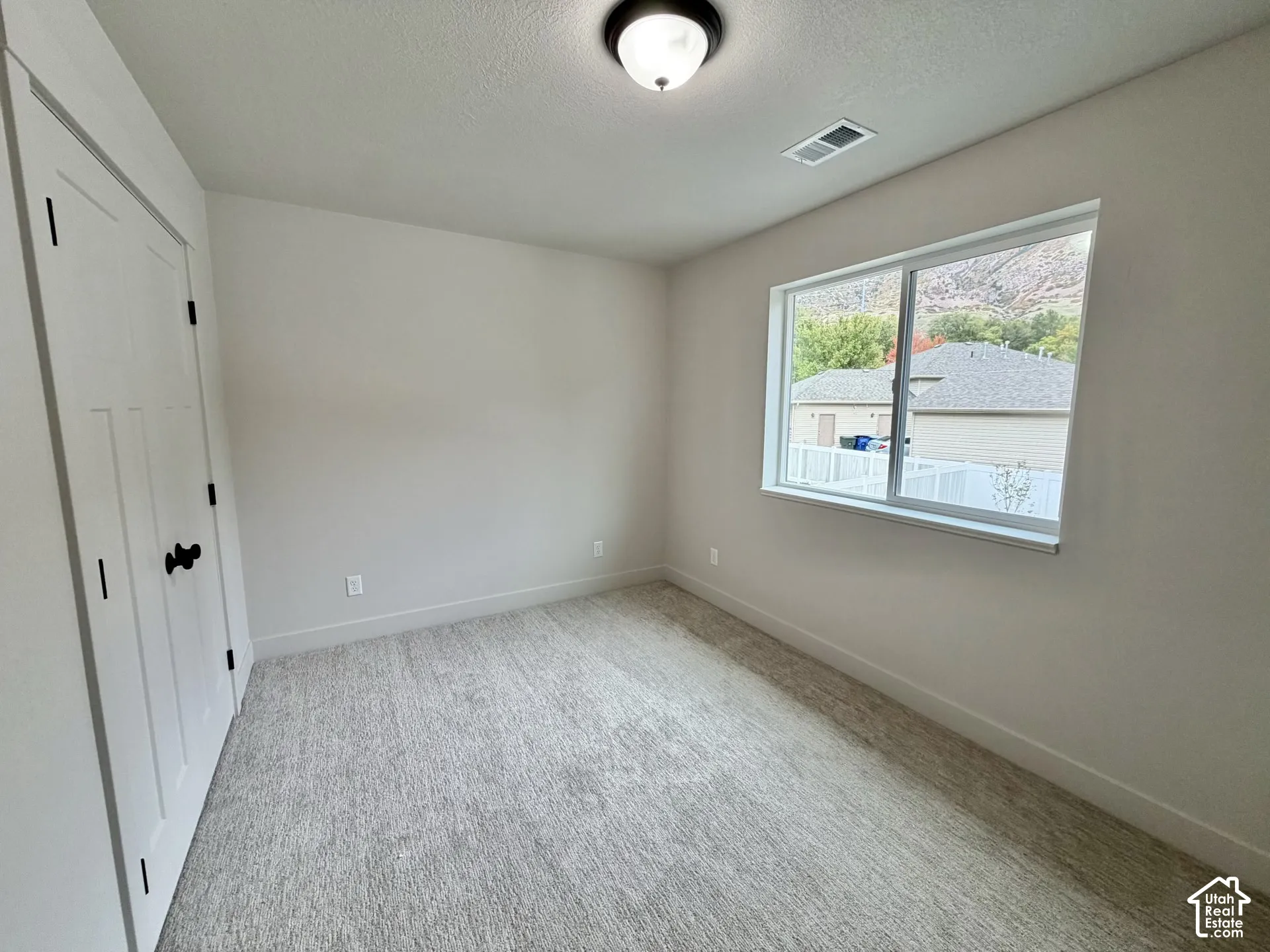 Neutral-toned interior featuring wall-to-wall carpeting, a dual-panel closet door with matte black hardware, and a sliding window with mountain scenery