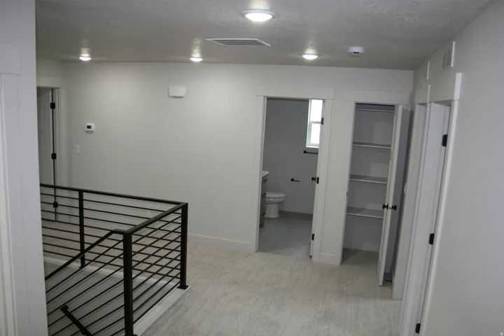Recessed ceiling lighting, modern black metal stair railing, light-toned flooring, interior doors with matte black hardware, and built-in shelving