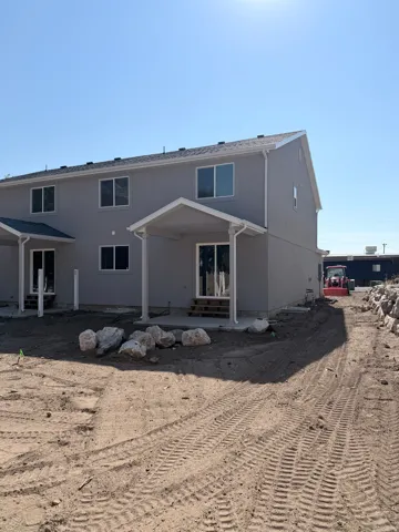 Two-story exterior with stucco finish, multiple windows, covered patio, and concrete slab