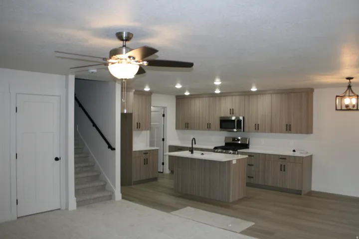 Contemporary kitchen with wood-finish cabinetry, white countertops, and stainless steel appliances