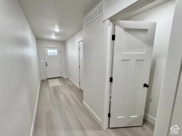 Entryway featuring wood-finish flooring, shaker-style interior doors with matte black hardware, and an exterior door with an inset glass panel