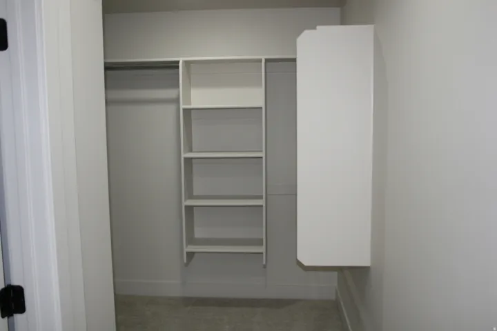 Built-in closet shelving, hanging rod, and wall-mounted storage cabinet