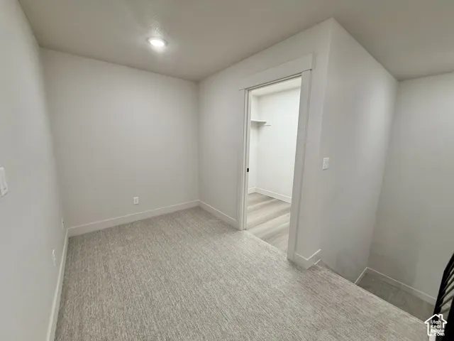 Neutral-toned carpeting, recessed ceiling lighting, and a walk-in closet featuring wood-finish flooring