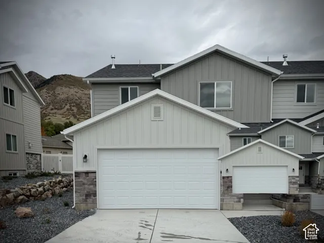 Exterior featuring board-and-batten siding, stone veneer accents, multi-gabled roofline, and mountain backdrop